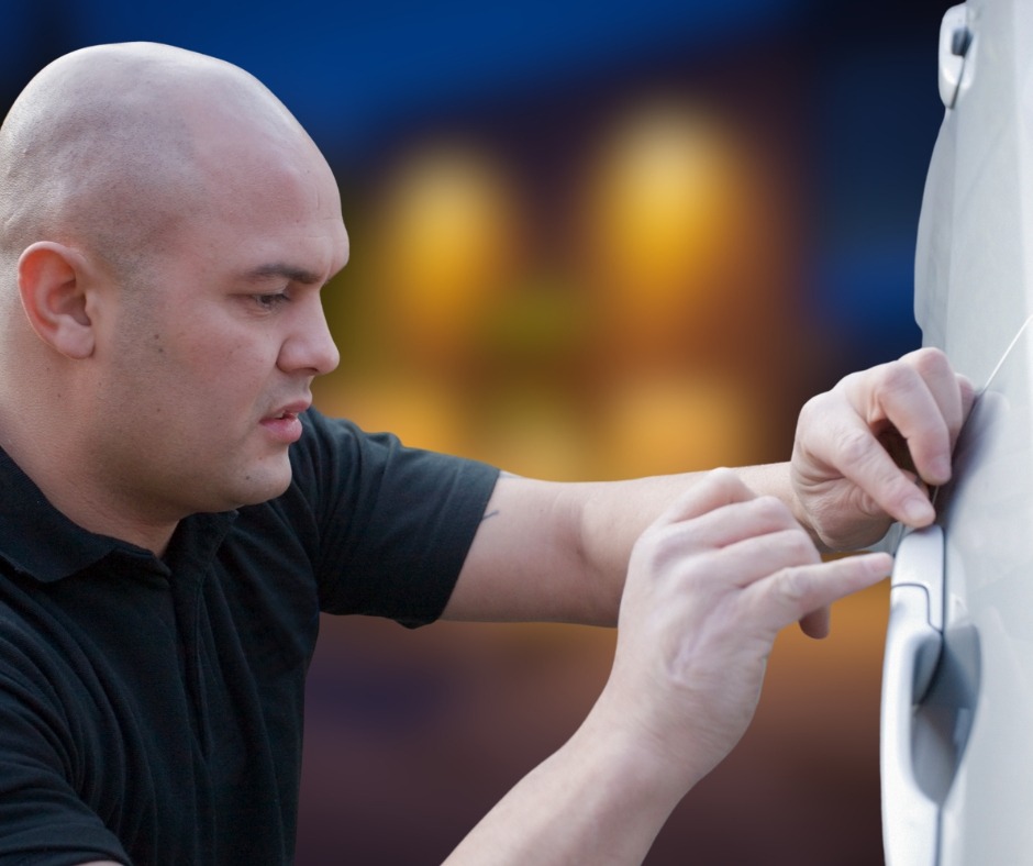 Uniformed locksmith technician picking the lock on a front door to gain entry during an after hours emergency callout.