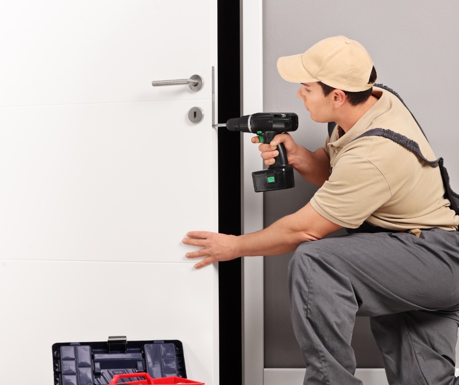 Two uniformed locksmiths working with lock picking tools and key cutter machine at client's home