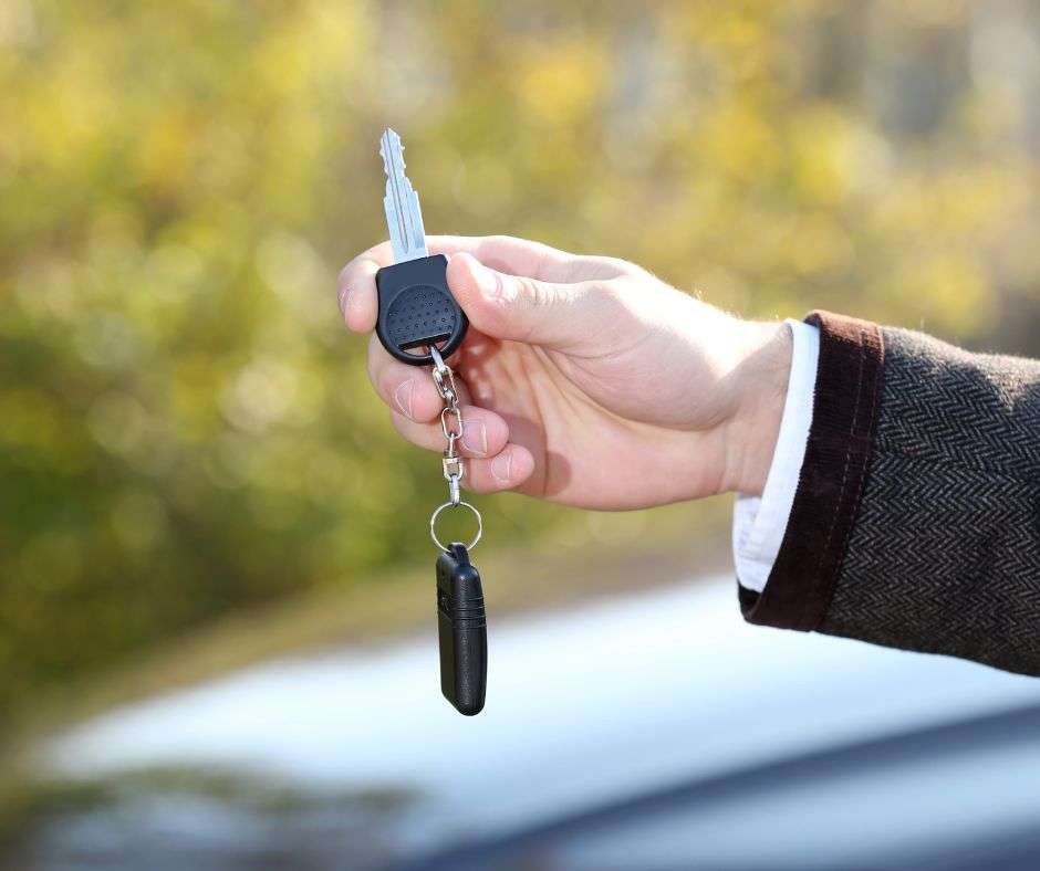 Man holding a key with a car in the background - Locksmith in Crawley